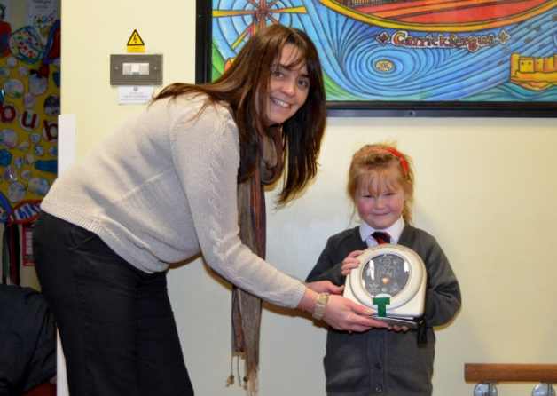 Model Primary School Principal Joanne Lyons and pupil Jenny Craig, receiving a HeartSine defibrillator donated to the school by Jenny's parents. Photo courtesy of the Carrick Times